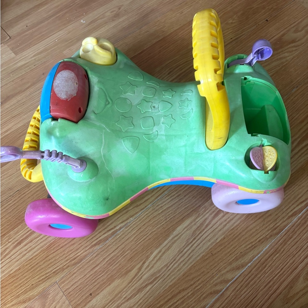 Green Toddler Ride-On Walker with Yellow Handle and Multi-Color Wheels